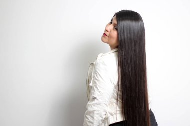 Latin genç kadın siyah saçlarının ne kadar ipeksi ve parlak olduğunu gösteriyor. Çok uzun, düz, çok mutlu ve güzel saçlarıyla gurur duyuyor.