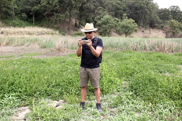 Latijnse Volwassen Man Met Hoed Shorts Zonnebril Gebruikt Zijn Mobiele — Stockfoto