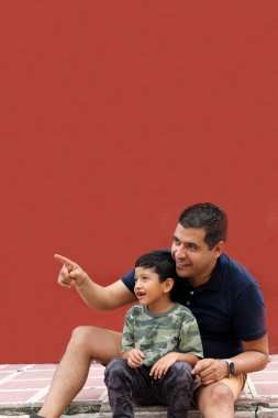 Bekar baba ve koyu renk saçlı Latin oğul birlikte oynayıp Babalar Günü 'nde ailece vakit geçirip zaferi kucaklayıp öperek kutluyorlar.