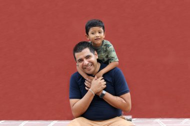 Bekar baba ve koyu renk saçlı Latin oğul birlikte oynayıp Babalar Günü 'nde ailece vakit geçirip zaferi kucaklayıp öperek kutluyorlar.