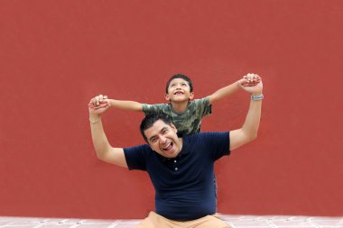 Bekar baba ve koyu renk saçlı Latin oğul birlikte oynayıp Babalar Günü 'nde ailece vakit geçirip zaferi kucaklayıp öperek kutluyorlar.