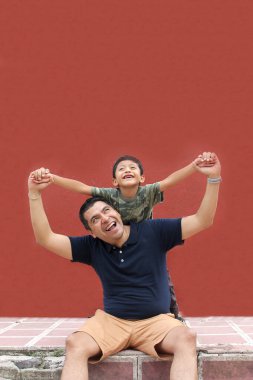 Bekar baba ve koyu renk saçlı Latin oğul birlikte oynayıp Babalar Günü 'nde ailece vakit geçirip zaferi kucaklayıp öperek kutluyorlar.