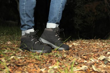 Siyah yürüyüş botlarıyla ormanda tehlikeli, maceraperest ve riskli bir gece yürüyüşü yapan birinin bacakları.