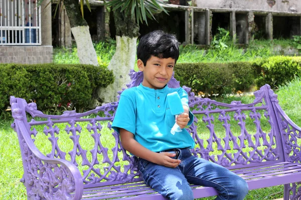 Poor Latino Dark Haired Boy Blue Shirt Sitting Park Bench — Zdjęcie stockowe