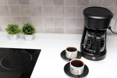 Freshly prepared coffee in a filter coffee machine served in white cups that is rich in antioxidants, fights Alzheimer's and Parkinson's, produces tachycardia and insomnia