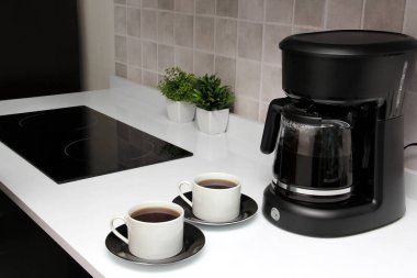 Freshly prepared coffee in a filter coffee machine served in white cups that is rich in antioxidants, fights Alzheimer's and Parkinson's, produces tachycardia and insomnia