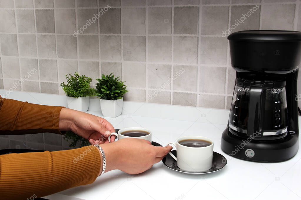 Freshly prepared coffee in a filter coffee machine served in white cups that is rich in antioxidants, fights Alzheimer's and Parkinson's, produces tachycardia and insomnia