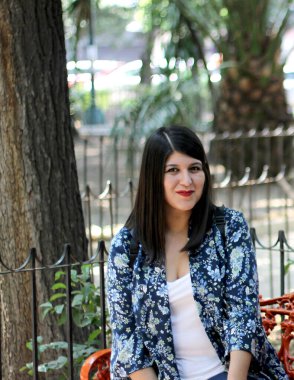 Latin adult woman sitting in a park enjoying the outdoors in relaxation and tranquility