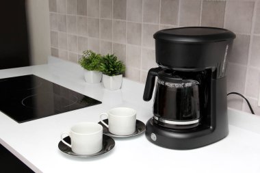 Freshly prepared coffee in a filter coffee machine served in white cups that is rich in antioxidants, fights Alzheimer's and Parkinson's, produces tachycardia and insomnia