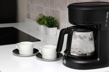 Freshly prepared coffee in a filter coffee machine served in white cups that is rich in antioxidants, fights Alzheimer's and Parkinson's, produces tachycardia and insomnia