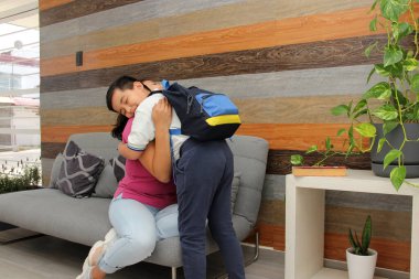 Latin kökenli anne ve oğlu okula üniforma ve sırt çantasıyla dönmeye hazırlanıyorlar.