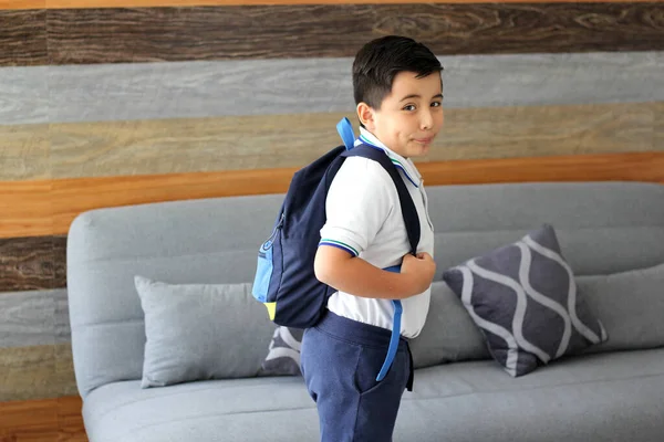 Hispanic male child ready for back to school with uniform and backpack takes his way to go to school healthy and safe
