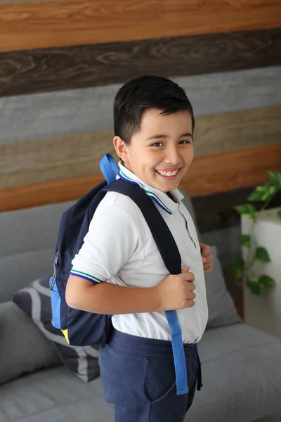 Hispanic male child ready for back to school with uniform and backpack takes his way to go to school healthy and safe