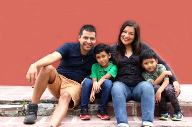 Latin, Hispanic family of mom, dad and children are sitting in the park they look happy enjoying quality time together in harmony
