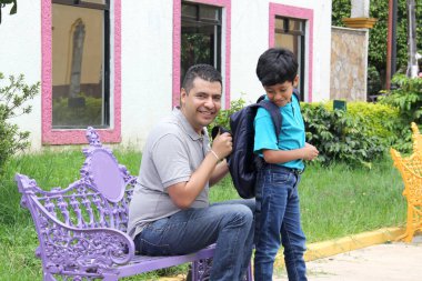 Latino dad checks his son's backpack on this return to school to check that he does not carry weapons or illegal substances