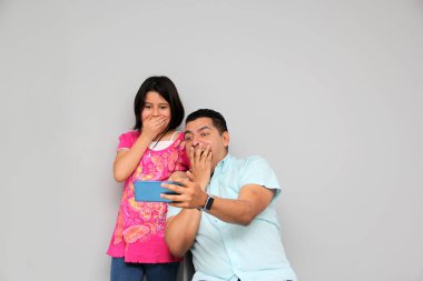 Hispanic Latino dad and daughter play, dance, surprise, enjoy, taking selfies using the cell phone spending quality family time