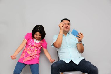 Hispanic Latino dad and daughter play, dance, surprise, enjoy, taking selfies using the cell phone spending quality family time