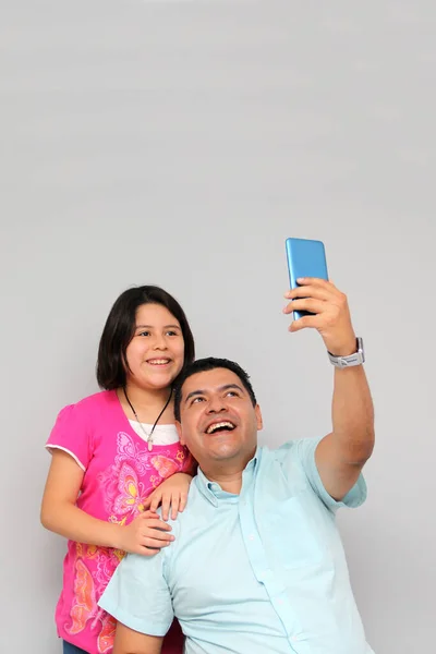 Hispanic Latino dad and daughter play, dance, surprise, enjoy, taking selfies using the cell phone spending quality family time