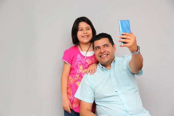 Hispanic Latino dad and daughter play, dance, surprise, enjoy, taking selfies using the cell phone spending quality family time