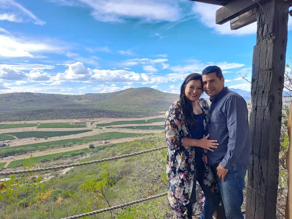 Couple of Latin adult man and woman enjoy the mountainous view of vineyards from a viewpoint you can see the land planted with vines