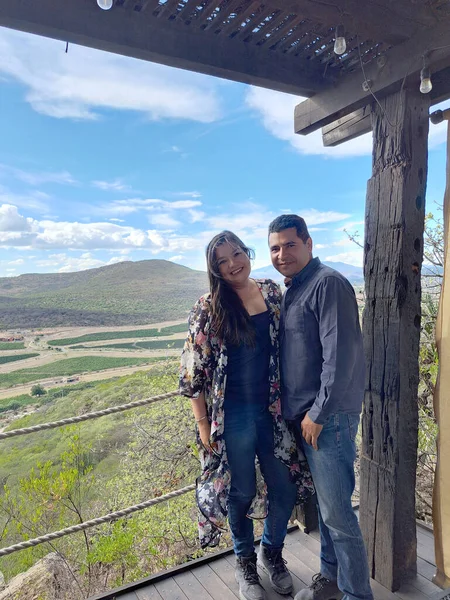 Couple of Latin adult man and woman enjoy the mountainous view of vineyards from a viewpoint you can see the land planted with vines