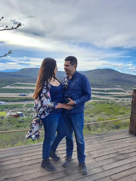 Couple of Latin adult man and woman enjoy the mountainous view of vineyards from a viewpoint you can see the land planted with vines