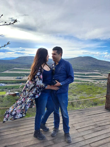 Couple of Latin adult man and woman enjoy the mountainous view of vineyards from a viewpoint you can see the land planted with vines