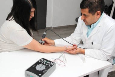 Latin doctor specialist neurologist performs a study of evoked potentials, diagnostic techniques with sensory stimuli and the recording of stimulated brain responses to a female patient.