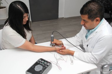 Latin doctor specialist neurologist performs a study of evoked potentials, diagnostic techniques with sensory stimuli and the recording of stimulated brain responses to a female patient.
