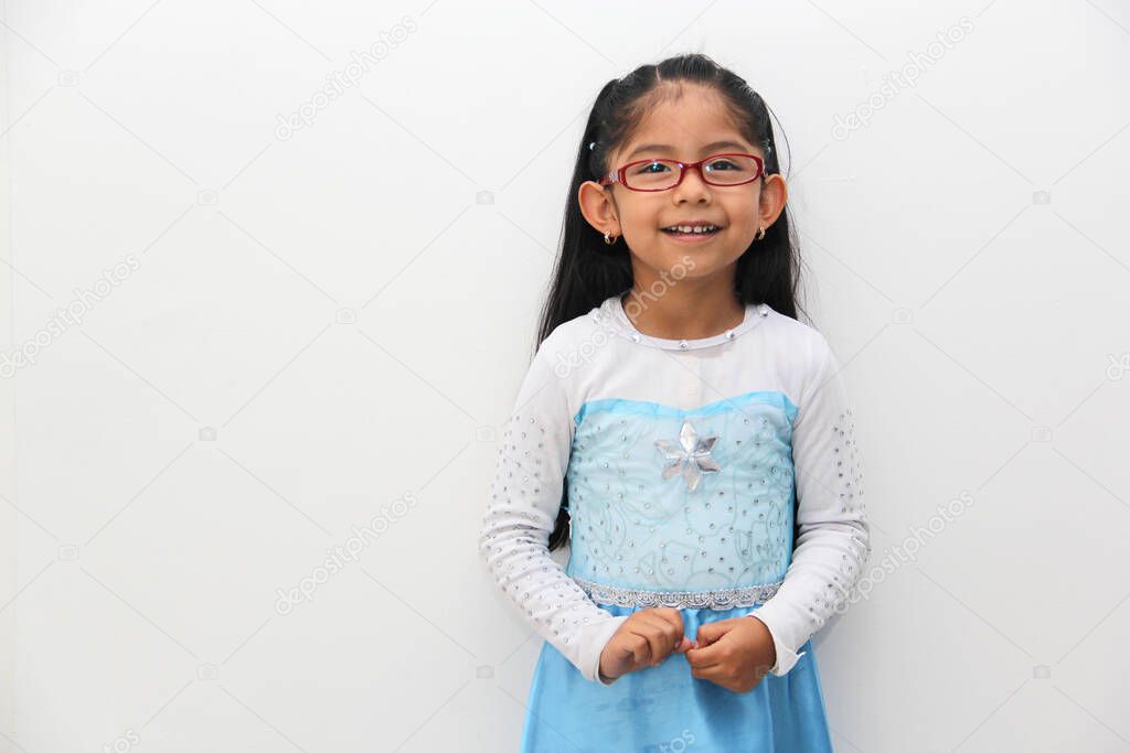 Poor 4-year-old Latin brunette girl is dressed as a happy princess with her costume to go to a children's party and feel strong and empowered