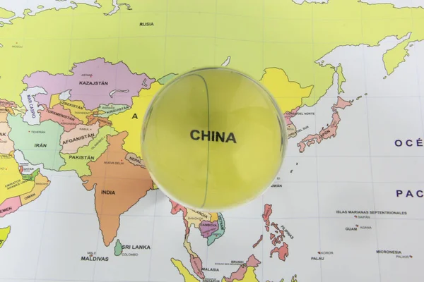 Crystal ball on a world map that highlights a country to highlight it as a magnifying glass and note its economic and financial importance in the world: China