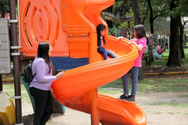 Boşanmış bekar anne, hafta sonları ya da tatillerde aileleriyle mutlu mesut vakit geçirmek için parkta kaydırakta iki kızıyla oynuyor.