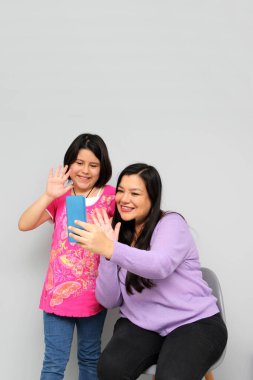 Latin kökenli anne ve kız oynuyor, dans ediyor, sürpriz yapıyor, eğleniyor, cep telefonu harcamak için ailece vakit geçiriyorlar.