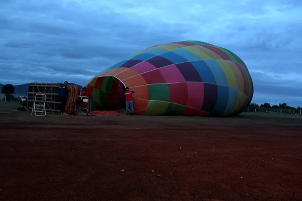 曇り空の飛行のための日の出時の熱気球の膨張と準備の過程 — ストック写真