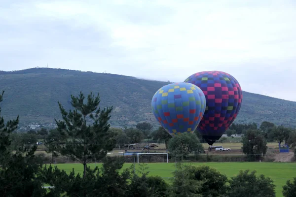 五彩缤纷的热气球在日出时分掠过植被和城市景观 — 图库照片