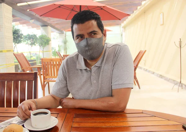 Latino man with protective mask having breakfast in restaurant, new normal covid-19