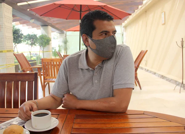 Latino man with protective mask having breakfast in restaurant, new normal covid-19