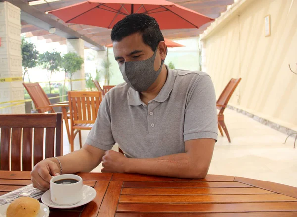 Latino man with protective mask having breakfast in restaurant, new normal covid-19