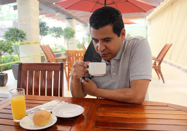 Latino man with protective mask having breakfast in restaurant, new normal covid-19