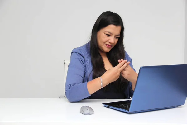 Latino adult woman speaks Mexican sign language with a deaf person through a laptop in a video call