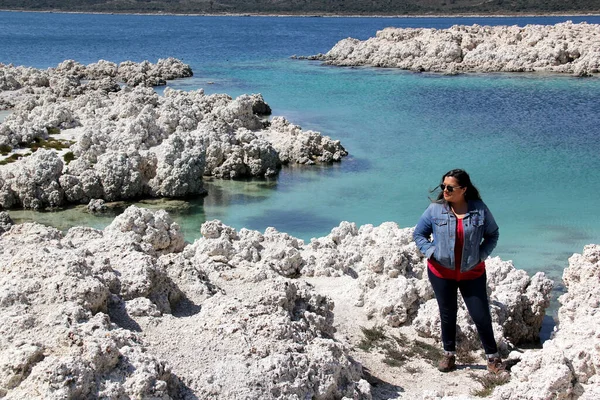 black hair latin woman in landscape of white rocks and water, turquoise blue lagoon. Alchichica Lagoon, Puebla Mexico