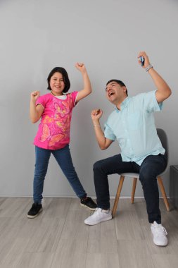 Hispanic Latino dad and daughter play, dance, surprise, enjoy, taking selfies using the cell phone spending quality family time