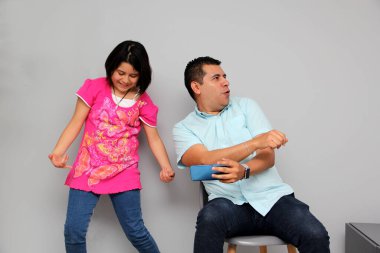 Hispanic Latino dad and daughter play, dance, surprise, enjoy, taking selfies using the cell phone spending quality family time