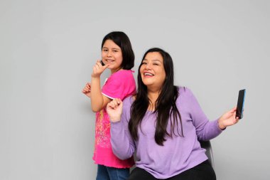 Latin kökenli anne ve kız oynuyor, dans ediyor, sürpriz yapıyor, eğleniyor, cep telefonu harcamak için ailece vakit geçiriyorlar.