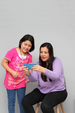 Latin kökenli anne ve kız oynuyor, dans ediyor, sürpriz yapıyor, eğleniyor, cep telefonu harcamak için ailece vakit geçiriyorlar.