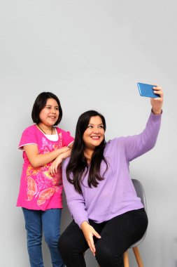 Latin kökenli anne ve kız oynuyor, dans ediyor, sürpriz yapıyor, eğleniyor, cep telefonu harcamak için ailece vakit geçiriyorlar.