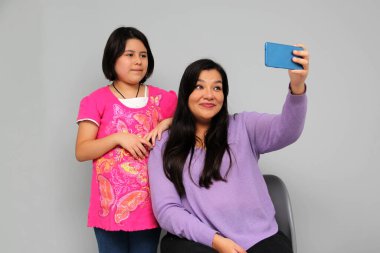 Latin kökenli anne ve kız oynuyor, dans ediyor, sürpriz yapıyor, eğleniyor, cep telefonu harcamak için ailece vakit geçiriyorlar.