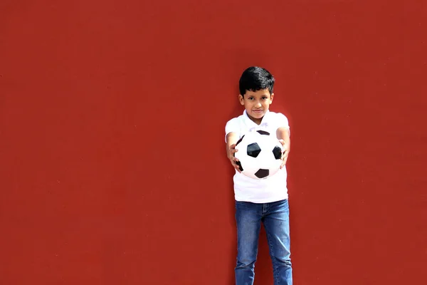 Latino 8-year-old boy plays with a soccer ball very excited that he is going to see the World Cup and wants to see his team win