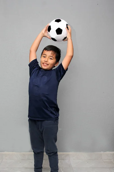 Hispanic Latino 8-year-old boy plays with a soccer ball very excited that he is going to see the World Cup and wants to see his team win