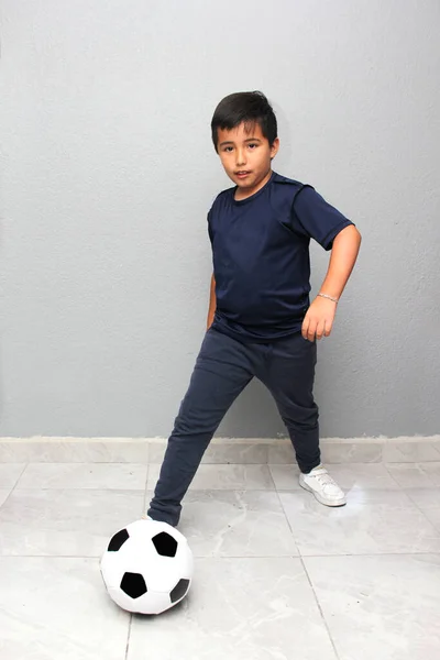 Hispanic Latino 8-year-old boy plays with a soccer ball very excited that he is going to see the World Cup and wants to see his team win